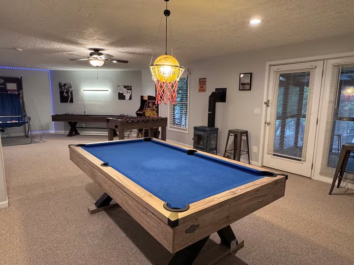 Blue pool table with arcade, basketball, and foosball in the game room
