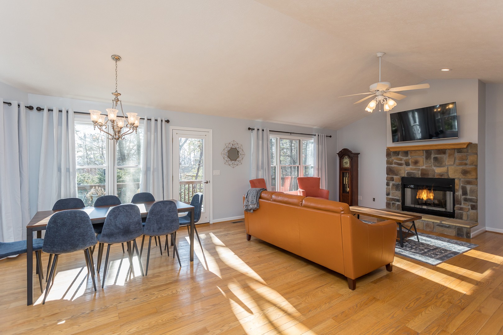Sunlit living and dining area with leather sofa and stone fireplace
