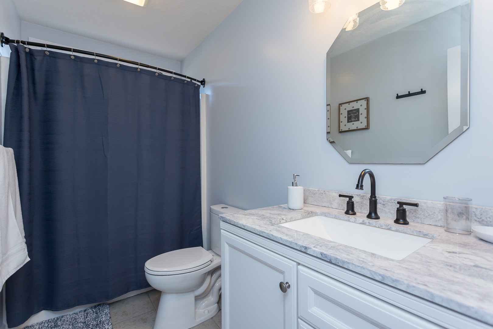 Bathroom with white vanity and blue shower curtain