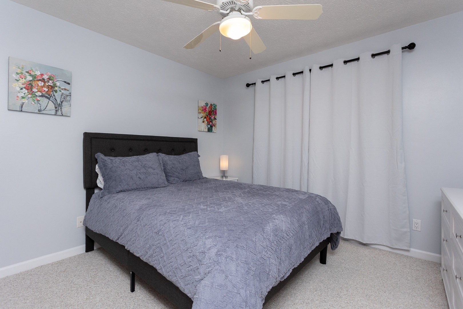 Queen bedroom with gray bedding and white curtains
