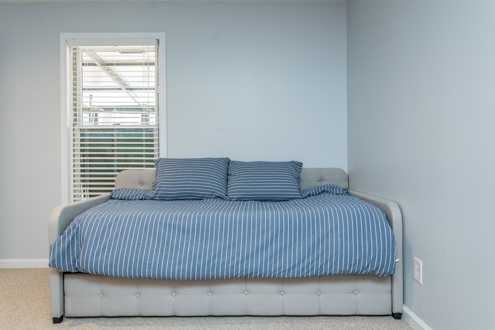 Twin daybed and trundle with blue striped bedding
